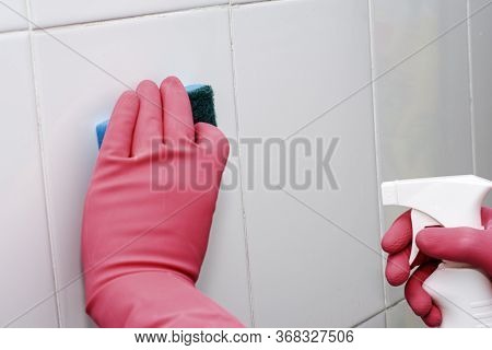 Bman In Rubber Household Gloves With A Sponge And Spray Washes A White Tiled Wall