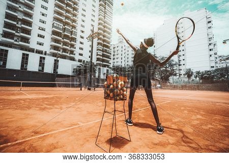 Wide-angle View From Behind Of A Young Slim Biracial Woman Aiming A Blow Before Hit A Tennis Ball Du