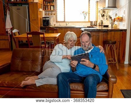 Happy Active Senior Man And Woman Video Calling Family Using Digital Tablet. Couple Enjoying Togethe