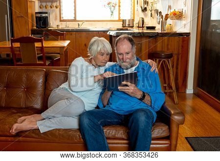 Happy Active Senior Man And Woman Video Calling Family Using Digital Tablet. Couple Enjoying Togethe