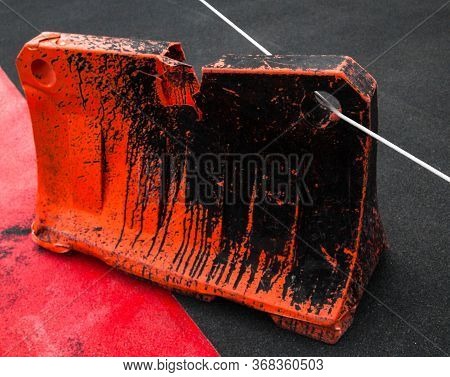 Orange Dirty Safety Barrier Tied With A Rope On The Road. Red Painted Asphalt. Red Road Surface Mark
