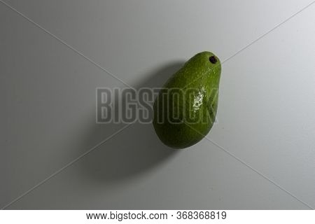 One Ripe Avocado Fruit In Light Green On A White Background. Top View