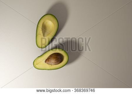 Two Halves Of Avocado Fruits With A Visible Core On A Light Background. Top View