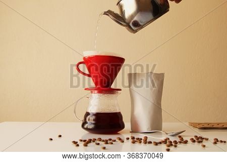 Filter Coffee Concept. Pouring Water Into The Ceramic Coffee Cup With Origami Filter Cups And A Pack