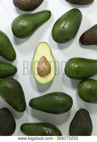 Avocado Fruit On A Contrasting Light Background. Whole And Cut With A Visible Core In The Center.