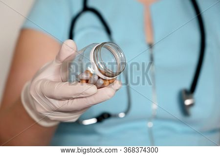 Doctor With Pills, Woman In Latex Gloves Giving Bottle Of Capsules. Concept Of Dose Of Drugs, Vitami