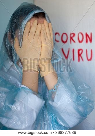 Woman In A Protective Suit Closing Her Face. Inscription Coronavirus In The Background. Coronavirus 