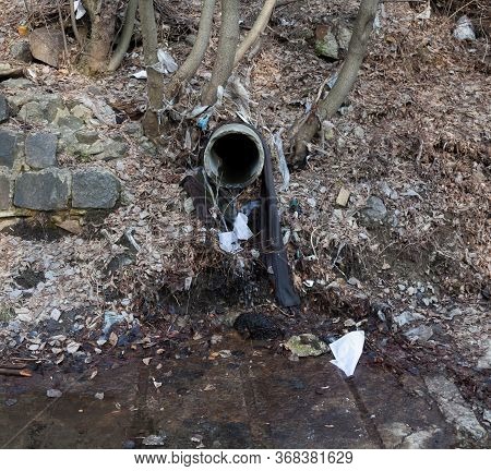 Concrete Run-off Pipe Discharging Water. Drain (drainage) Pipe. Garbage Around The Pipe. Environment