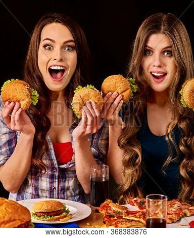 Group women eat best hamburger and pizza in burger bar . Friends take fast food drink cola and chatting.