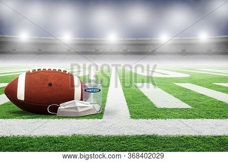 Football On Field Of An Empty Stadium With Hand Sanitizer And Medical Face Mask. Concept Of Football