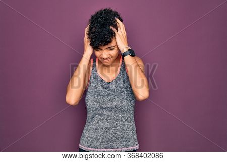 Young beautiful african american afro sportswoman doing exercise wearing sportswear suffering from headache desperate and stressed because pain and migraine. Hands on head.