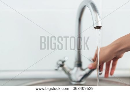 Woman Hand Opening Silver Faucet Or Water Tap With Metal Washing Sink In The Kitchen .