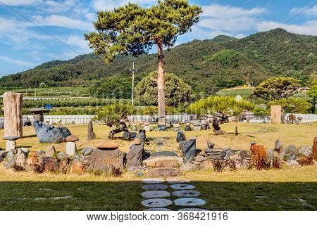 Gimcheon, South Korea; May 24, 2020: Evergreen Tree In Center Of Circular Rock Garden In Under Cloud