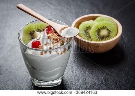 Greek Yogurt In A Glass With Kiwi On Black Stone Slab