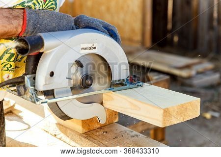Manual Circular Circular Saw On Wood Metabo. A Man At A Construction Site Saws A Wooden Board Bar Cl