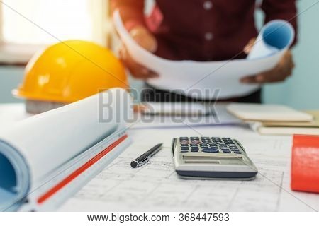 Construction Working Tool, Calculator, Blueprint And Safety Helmet On Architect Workplace Desk With 