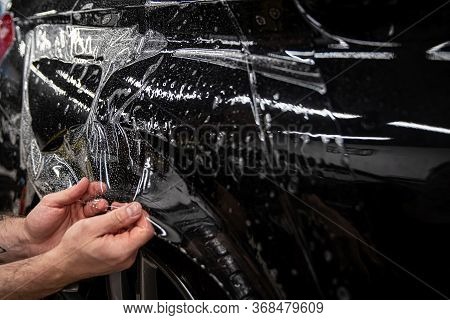 Car Wrappping. Man Car Detailing Studio Worker Appling Transparent Protection Foil On Car Body.