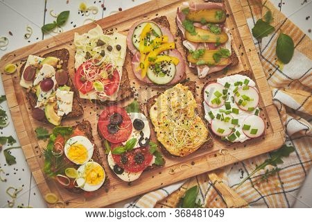 Tasty, homemade small sandwiches with various ingredients served on wooden chopping board. Vege kitchen concept.