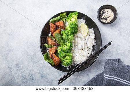 Vegan Teryaki  Tempeh Or Tempe Buddha Bowl  With Rice, Steamed Broccoli, Spinach  And Lime On Gray B