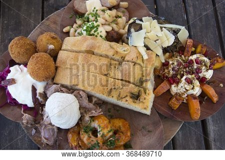 Gourmet Antipasto Board With A Selection Of Cured Meats, Local Cheeses, Pickled Vegetables, Herbed H