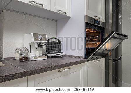 Electric appliances such as espresso coffee maker, sandwich maker and oven in modern minimalistic white kitchen interior