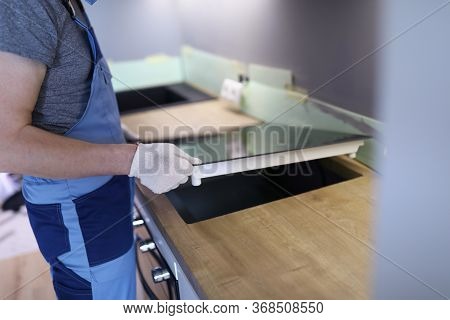 Close-up Of Professional Worker Setting Cookstove In Kitchen Room. New Modern Cooker. Man Wearing Pr