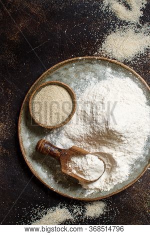 Raw Fonio Flour And Seeds With A Spoon On A Plate On Dark Background Top View. Alternative Flour