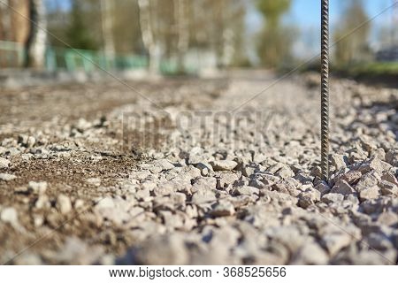 Rusty Reinforcement Rod Against The Background Of A Road Being Repaired In A Blur.