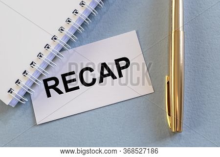 Recap Word On White Card Paper Sheet On Blue Table With White Planner And Golden Pen