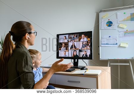 Back View Of Young Mother In Eyeglasses Is Talking Online, She Using Lpc For Video Meeting With Empl