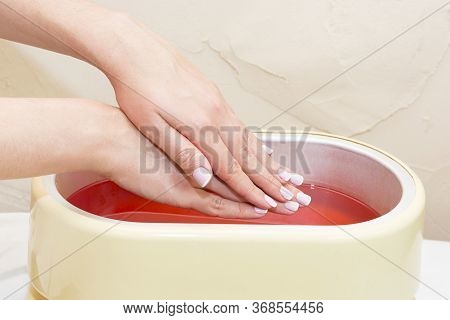 The Process Of Paraffin Therapy Of A Female Hand Is Shot Close Up In A Beauty Salon.