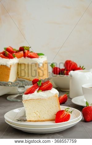 Angel Food Cake With Whipped Cream And Slices Of Fresh Strawberries On Top On A Concrete Background.