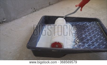 The Primer Is Poured. Wall Primer Mix. A Worker Pours A Primer From A Black Canister. The Worker Pou