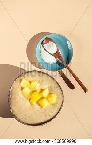 Collagen Powder And Healthy Smoothie From Banana, Pineapple And Gluten Free Oats In The Coconut Shel