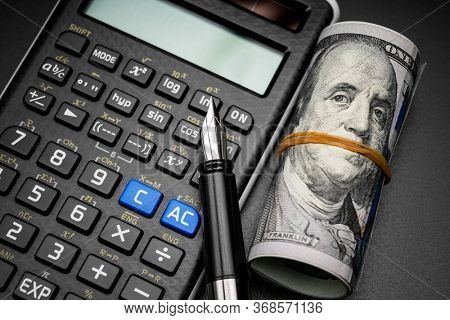 calculator and a roll of us dollarts on desk.
