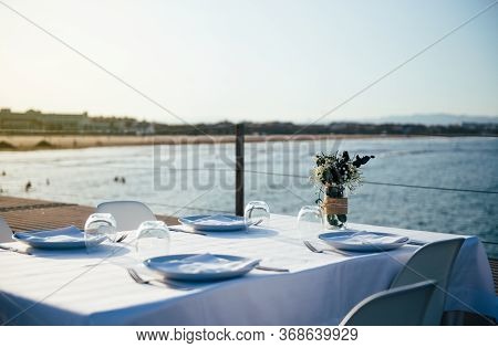 Restaurant Table With White Tablecloth On The Terrace By The Sea Concept Of Return To Normal During 