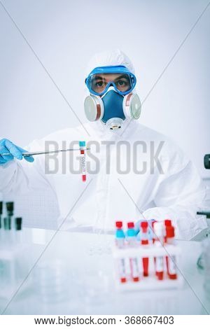 COVID-19. Doctor, microbiologist, scientist in a protective suit, makes a research on blood samples of infected people in the laboratory. Coronavirus test.