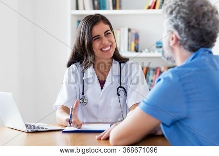 Laughing Mexican Female Doctor Talking With Patient At Hospital