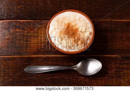 White Corn Cooked With Milk Known As Canjica, Canjicão Or Mungunza, In A Rustic Bowl On Wooden Table