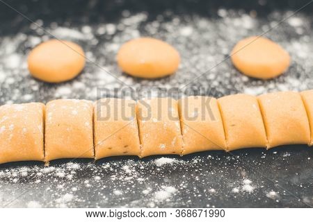 Molding Yellow Dough Into Corn Bread Over Black Table With Some Flour. Flat Lay Of Homemade Healthy