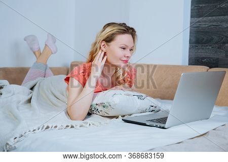 Young Smiling Woman Is Lying On Her Sofa At Home And Shopping Online While Lockdown.