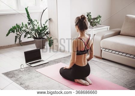 Caucasian Woman Sitting In Front Of The Laptop And Practice Yoga At Home Dressed In Sportswear On A 