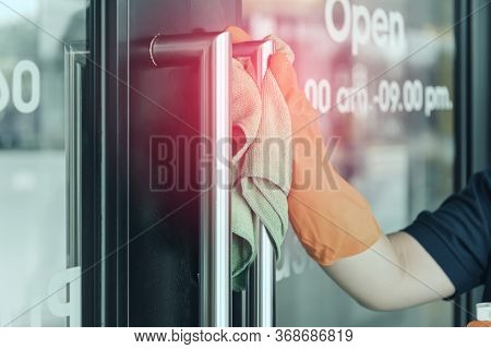 Woman Hand In Protective Orange Rubber Gloves Holding Green Microfiber Cleaning Cloth And Wiping Dus