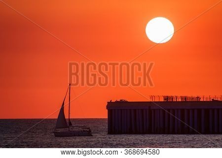 Beautiful Red And Orange Sunset Over The Sea In A Cloudy Sky. The Sun Goes Down Over The Sea. Dramat