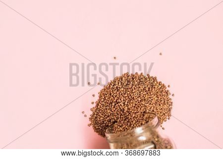 The Buckwheat In A Glass Jar Is Scattered On A Pink Background.place For Text