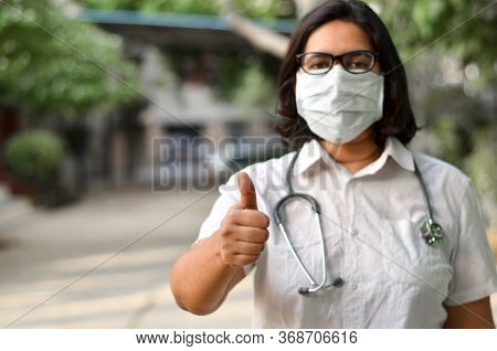Portrait Of A Young Medical Healthcare Female Worker Showing Thumbs Up Sign With Her Right Hand Wear