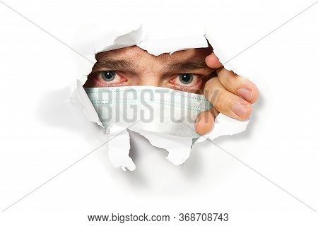 Man In Medical Mask Peeping Through Hole On Paper. Male Eye Looking Through Hole. Isolated On White 