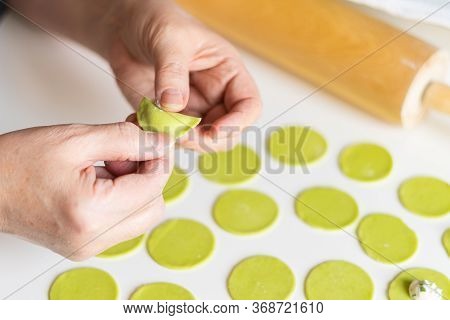 The process of sculpting dumplings. Green dumplings with cheese. Russian dumplings