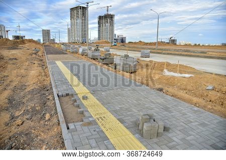 Laying Paving Slabs And Borders At Construction Site. Process Of Installing Paving Bricks In The Tow