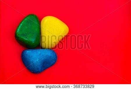 Multi Color Natural Pebbles Green, Blue And Yellow Stone Isolated On Red Background With Space For C